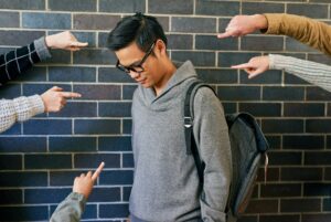 Cropped shot of a young male university student being bullied while standing in a campus corridor