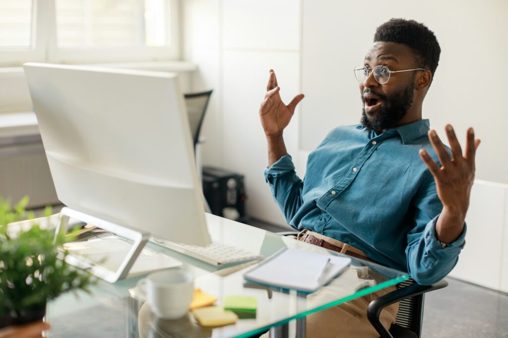 Got job promotion. Excited black businessman celebrating great news and luck, looking at computer